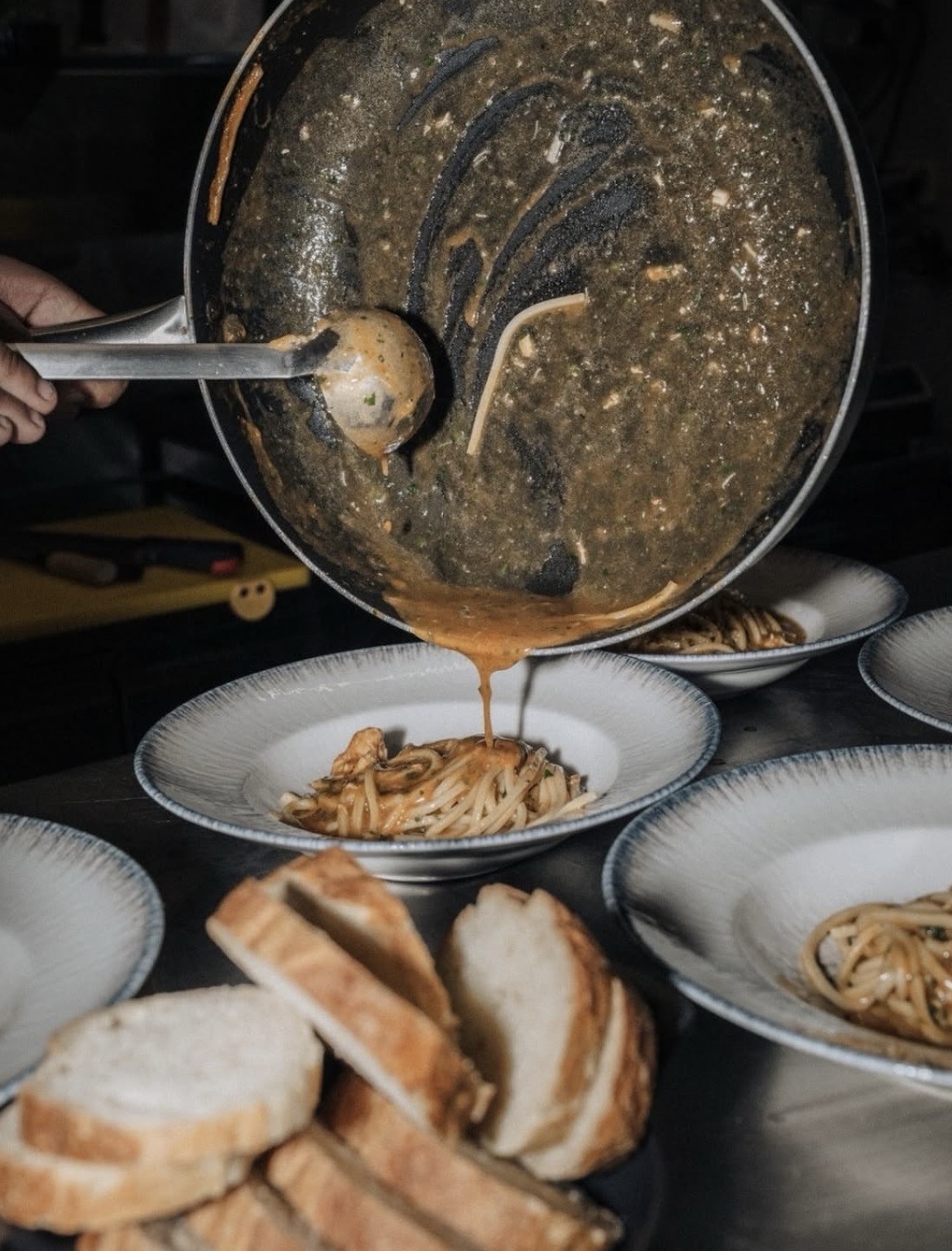 Padella di pasta di mare versata nei piatti con pane casereccio